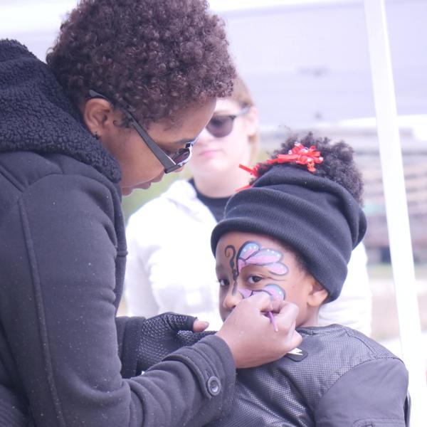 Child gets their face painted like a butterfly